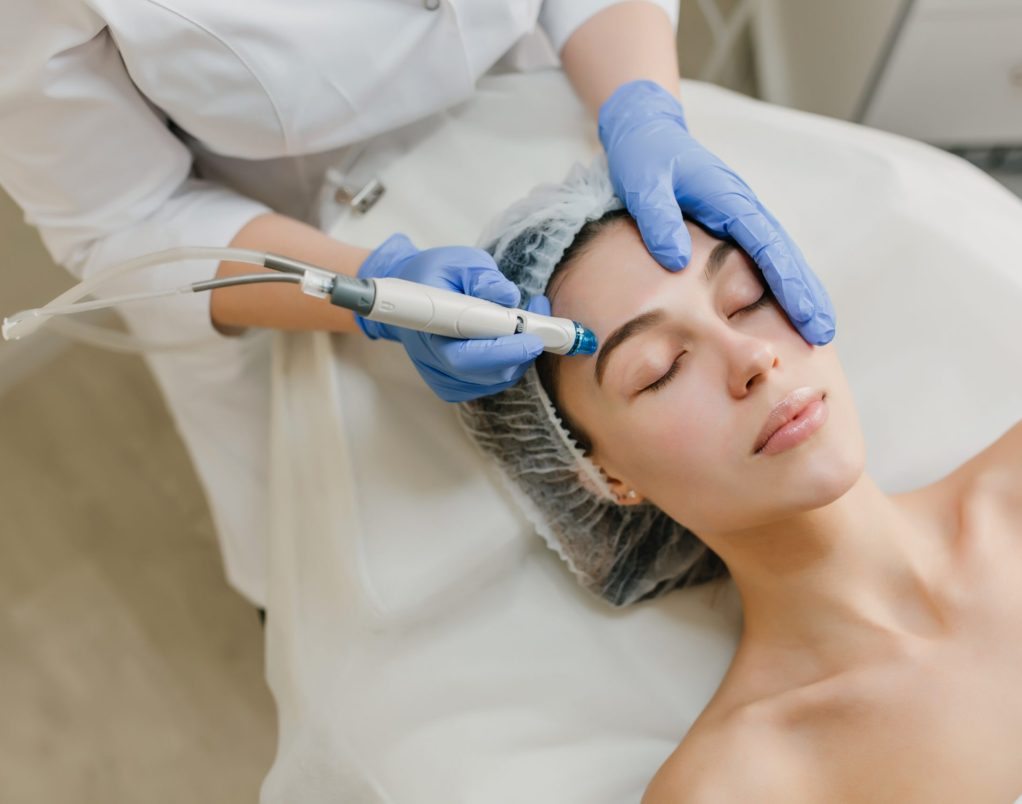 View from above rejuvenation of beautiful woman enjoying cosmetology procedures in beauty salon. Dermatology, hands in blue glows, healthcare, therapy, botox